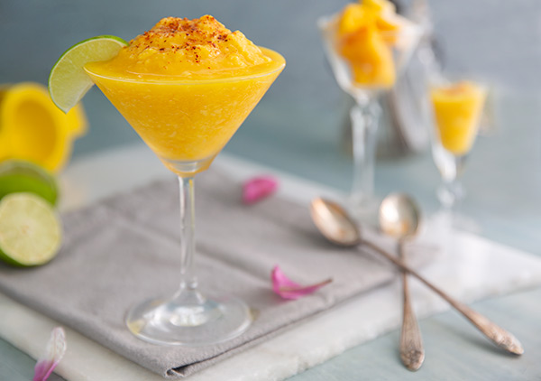 Quick Mango Sorbet in a martini glass with a lime wedge and chili powder on top