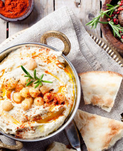Hummus, chickpea dip, with rosemary, smoked paprika and olive oil in a metal bowl with pita