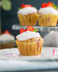 Strawberries and Cream Cupcakes on a glass pedestal with a cupcake on a plate in front