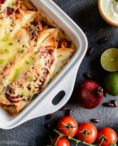 Traditional mexican enchiladas with chicken meat, spicy tomato sauce, corn, beans and cheese