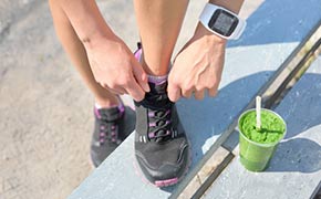 Tying tennis shoes, ready for a workout with green smoothie