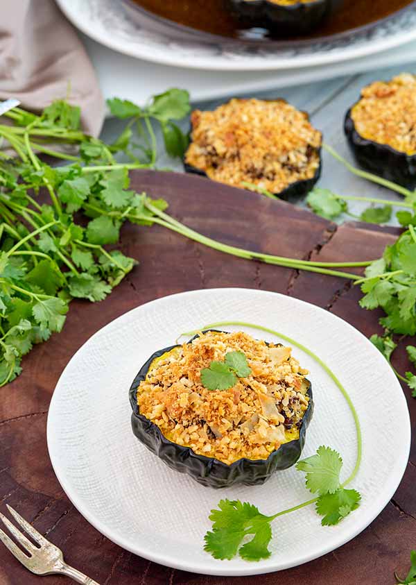 Quinoa Stuffed Baked Acorn Squash on a plate, garnished with fresh herbs