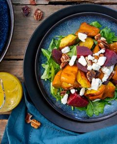 Gluten Free Roasted Acorn Squash Salad on a plate with dressing on the side
