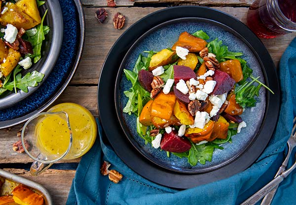 Gluten Free Roasted Acorn Squash Salad on a plate with dressing on the side