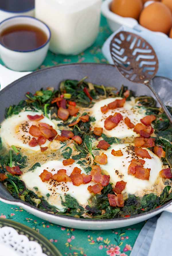 Spicy Kale and Eggs in a skillet with coffee and milk in the background