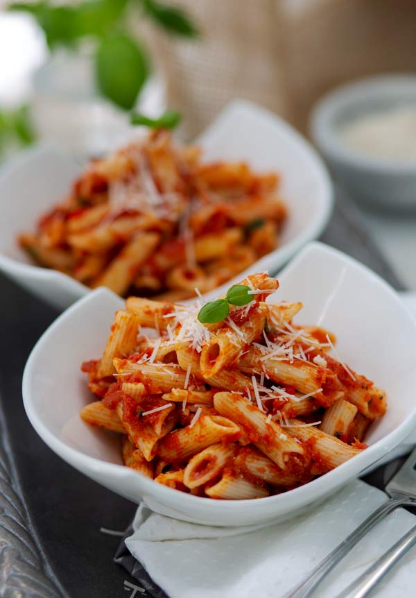 Gluten Free Penne Arrabbiata Recipe in white bowls with Parmesan cheese on top