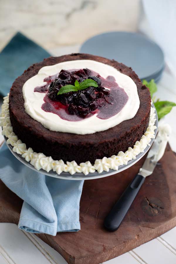 Cherry Filled Chocolate Cake on a serving platter topped with whipped cream and cherries