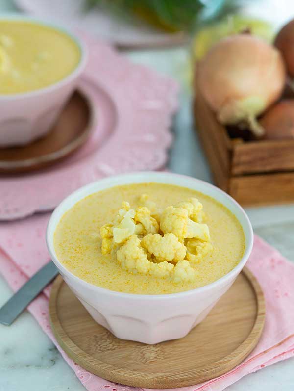 Curried Cauliflower Soup with cauliflower on top in a white bowl