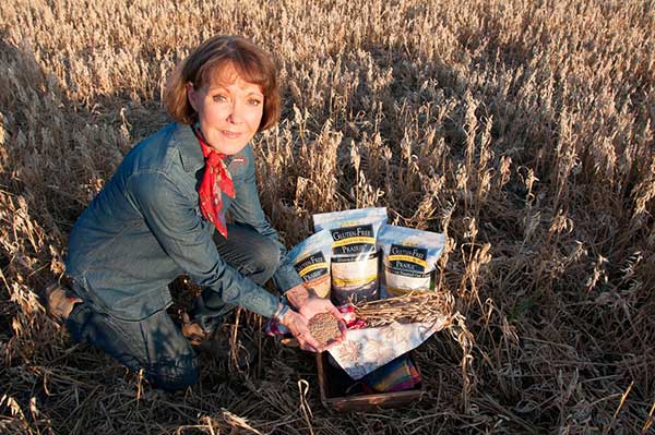 Gluten-Free Prairie Founder Deb Wheaton in a field holding oats