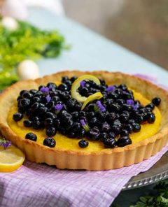 Lemon Blueberry Pie on a plate with fresh blueberries.