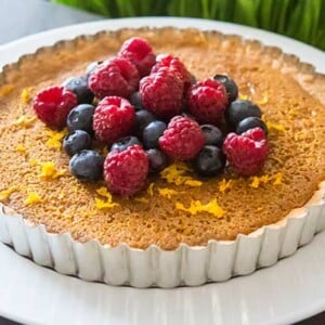 Meyer Lemon Tart on a white plate topped with fresh berries.