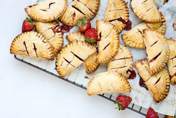 Roasted Strawberry Hand Pies on a cooling rack with fresh strawberries as garnish