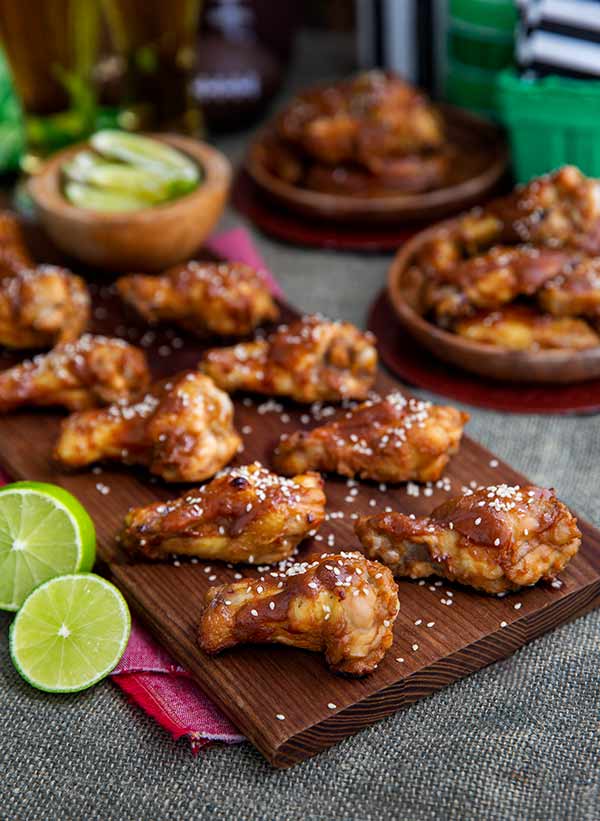 Sweet and Spicy Wings on a wooden cutting board with lime wedges