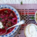 Borscht with bowls of sour cream and sauerkraut on the side