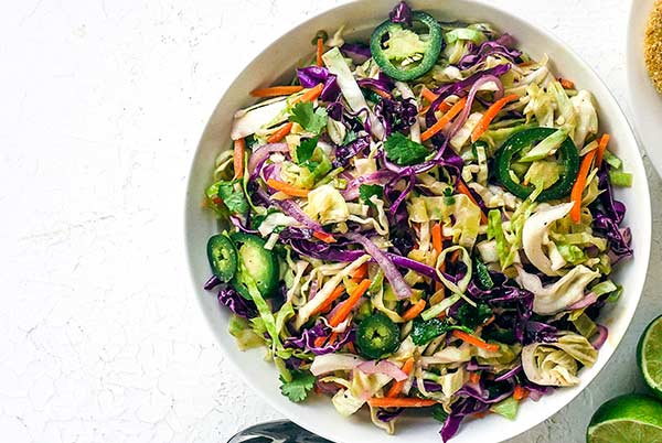 Jalapeno Coleslaw with purple cabbage in a white serving bowl