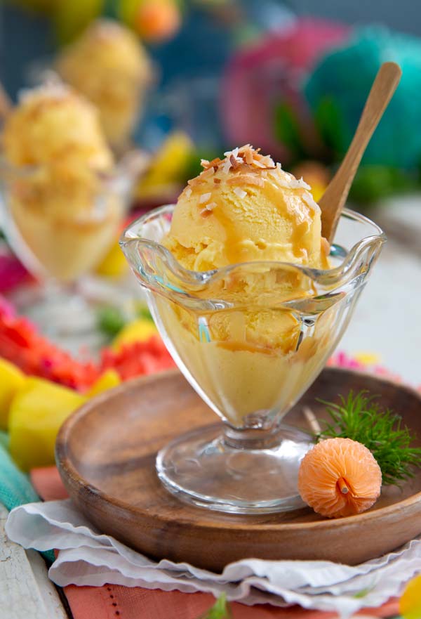 Mango Coconut Ice Cream in a decorative glass with bright colors in the background