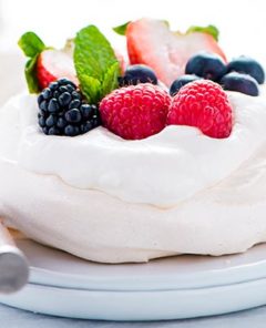 Closeup of a Mini Pavlova topped with fresh berries on a white plate