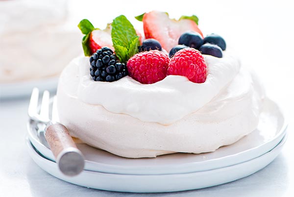 Closeup of a Mini Pavlova topped with fresh berries on a white plate