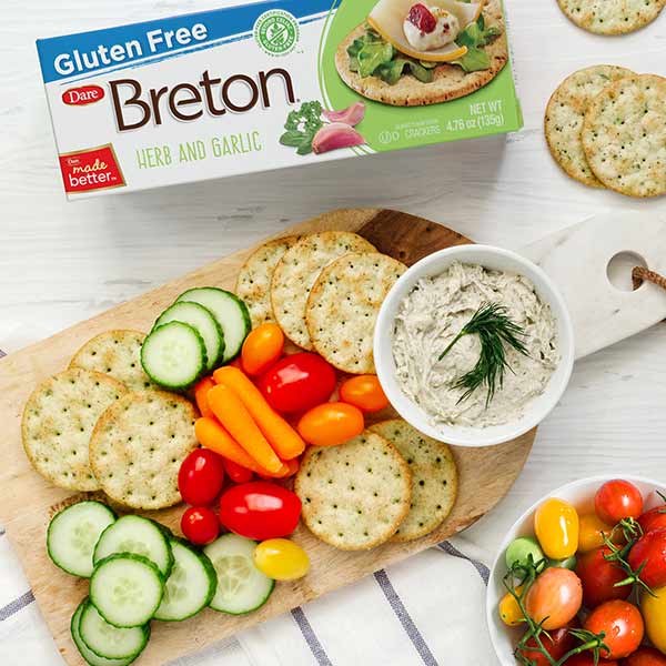 Breton Herb and Garlic Crackers on a wooden cutting board with dip in a bowl and fresh vegetables