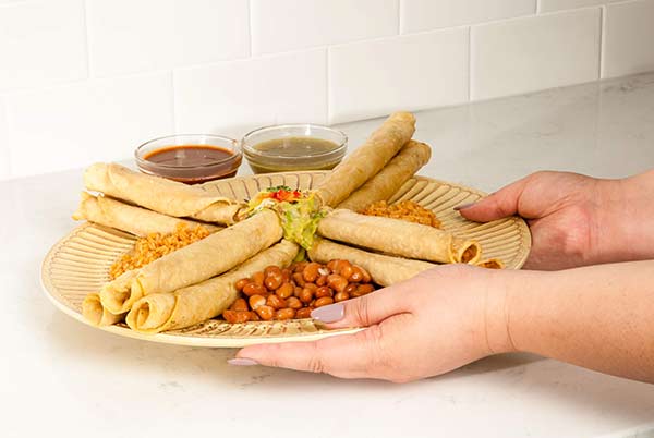 Starlite Cuisine Taquitos with Dipping Sauces on a tray with a woman's hands holding the tray out to serve