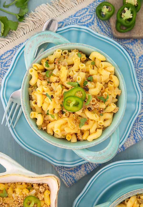 Vegan Jalepeno Mac n Cheese in a blue serving bowl with jalapenos in the background
