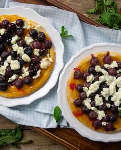 Apricot and Berry Flatbreads garnished with mint leaves on white plates on top of a wooden serving tray