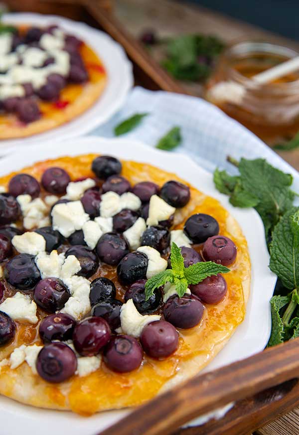 Close up of Apricot and Berry Flatbread garnished with mint leaves on a white plate