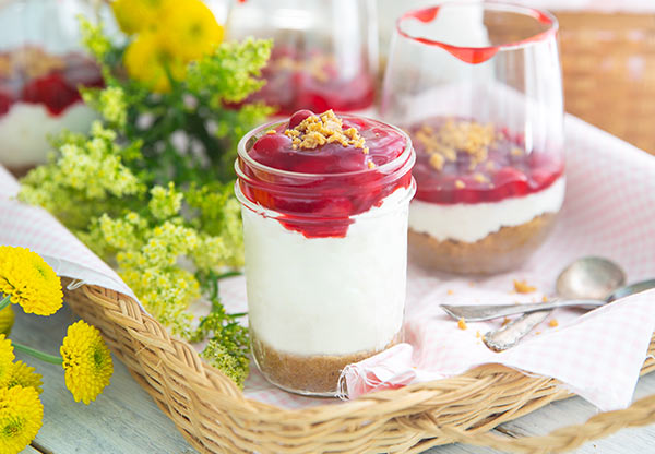 Gluten-Free Cherry Cheesecake-in-a-Jar with bright yellow flowers in the background