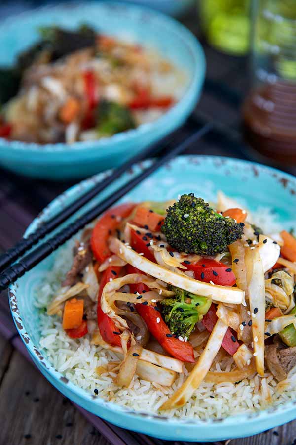 Close up of Spicy Beef and Vegetable Stir-Fry in a blue bowl with chop sticks