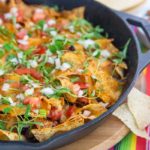 Taco Skillet dish in a cast iron skillet with cilantro on top with a colorful striped tablecloth underneath