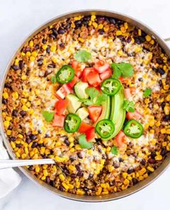 Beef Burrito Skillet Casserole in a stainless steel skillet topped with fresh jalapeno, tomatoes, and avocado