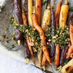 Blistered Carrots with Summer Herb Gremolata on a baking sheet with parchment paper and a wire slotted serving utensil