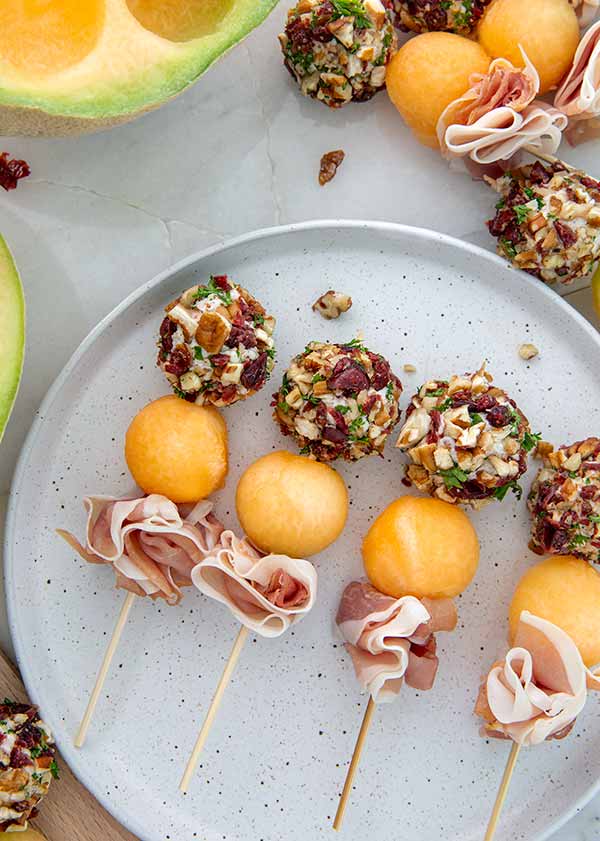 Goat Cheese Skewers with balls of goat cheese covered in chopped nuts, prosciutto slices, and balls of cantaloupe