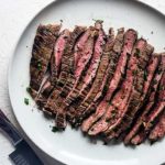 Herb-Marinated Flank Steak sliced into strips on a white plate