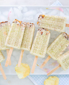 Honeydew Macadamia Ice Pops on a bed of ice cubes on a white rectangular plate