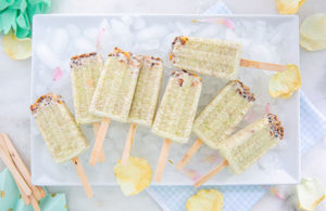 Honeydew Macadamia Ice Pops on a bed of ice cubes on a white rectangular plate