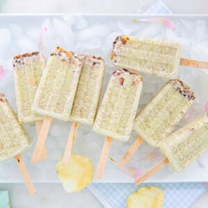 Honeydew Macadamia Ice Pops on a bed of ice cubes on a white rectangular plate