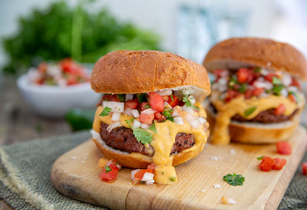 Plant-Based Queso Burger on a wooden cutting board with cilantro in the background