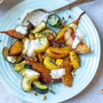 Roasted Summer Squash with Peaches and Pine Nuts on a white plate drizzled with a cream sauce