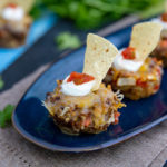 Tex-Mex Meatloaf Cupcakes on a dark blue serving plate, topped with sour cream, salsa, and a tortilla chip