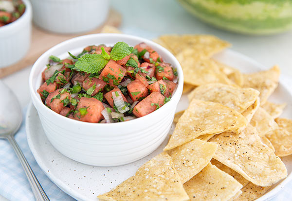 Watermelon Salsa in a white bowl with homemade tortilla chips on the side