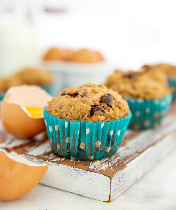 Banana Chocolate Chip Muffin in teal and white polka dot muffin wrapper on a wooden cutting block