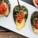 Cheese-Stuffed Poblano Peppers with Salsa on a white rectangular plate