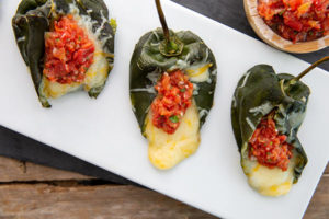 Cheese-Stuffed Poblano Peppers with Salsa on a white rectangular plate