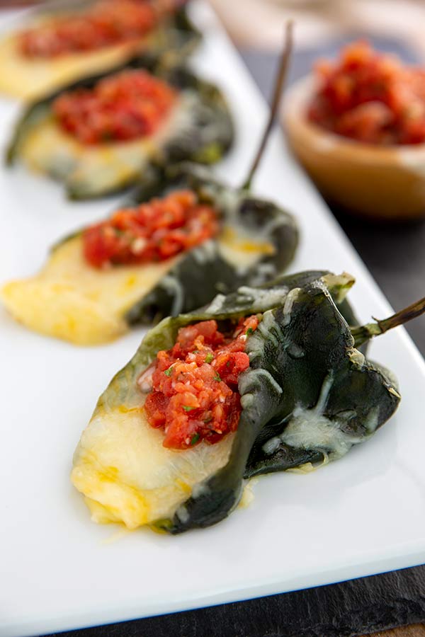 Close up of Cheese-Stuffed Poblano Peppers with Salsa on a white plate
