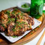 Closeup of Grilled ACV Chicken Thighs on a white plate on top of a wooden cutting board