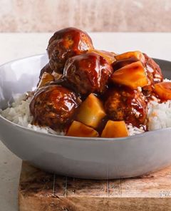 Vegetarian Sweet and Sour Meatballs over rice in a gray bowl on a cutting board
