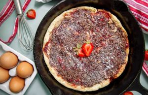 Chocolate and Strawberry Baked Pancake in a cast iron skillet with fresh strawberries on top