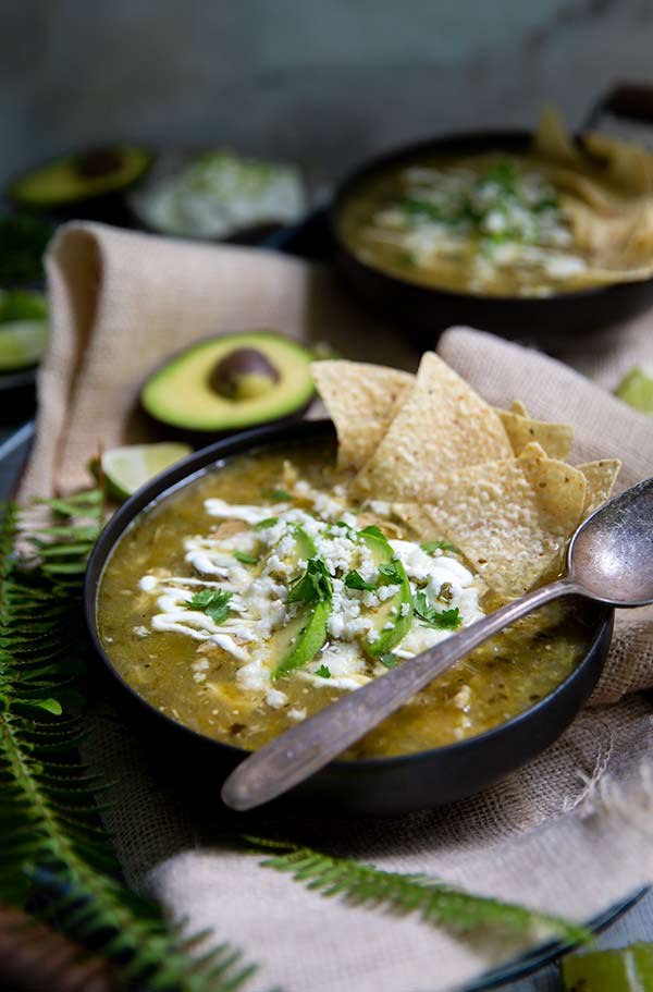 Tomatillo Soup in a black bowl with corn tortilla chips inside