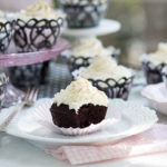 Mocha Cupcakes with white frosting on a delicate white plate with a light pink napkin underneath and cupcakes in the background